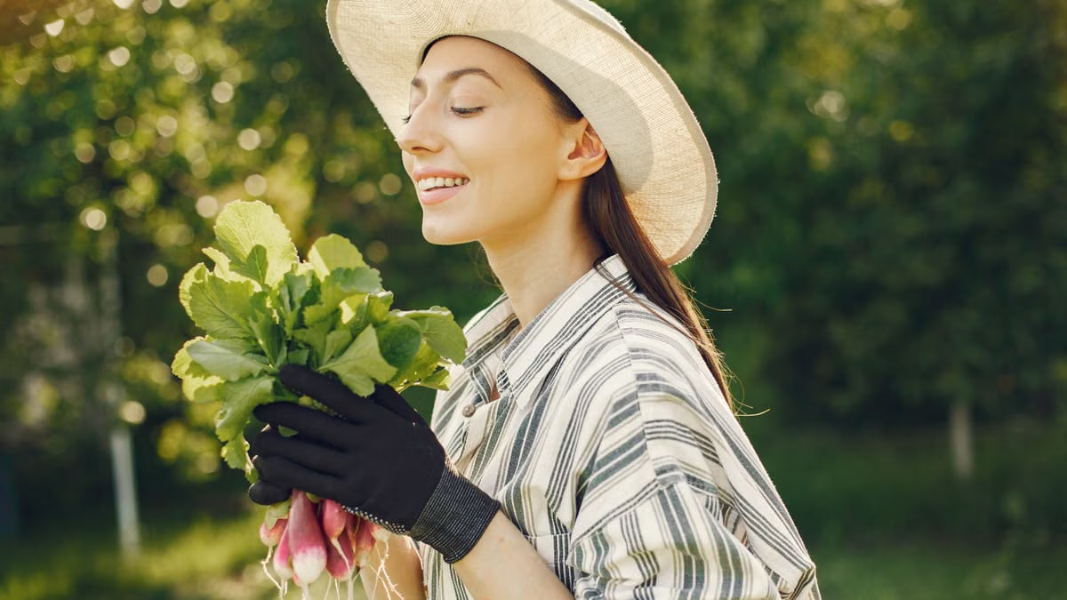 Happy woman enjoying a fresh harvest of radishes in a sunny garden.
