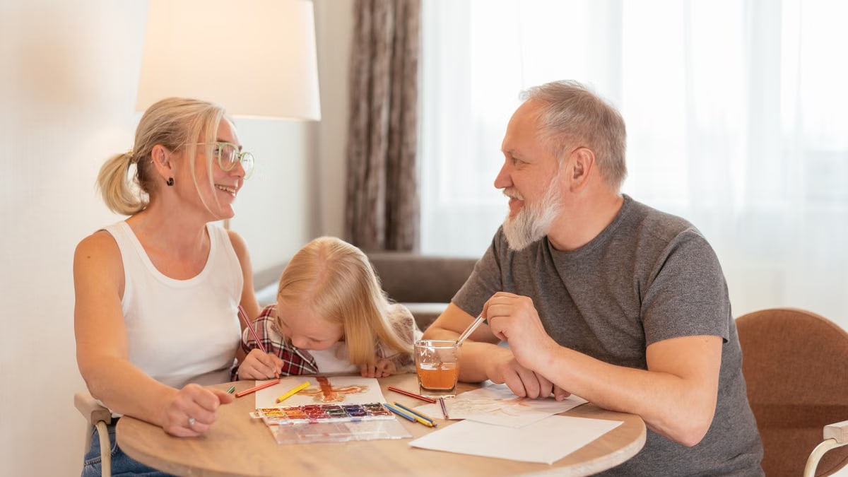 Grandparents and a child bond over painting at a cozy home setting, smiling and focused.